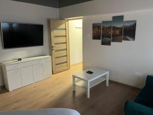a living room with a flat screen tv and a table at Mazepa Apartment in Galaţi