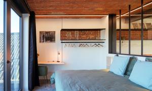1 dormitorio con cama y pared de ladrillo en La Camuche de Marcel Michiels, appartement de 70 m2 avec patio en Tournai