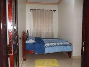 a bedroom with a bed with a blue comforter and a window at Malaika Furnished Apartments in Kampala