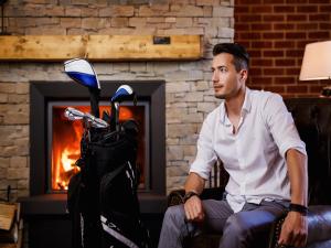 卡羅維發利的住宿－Cihelny Golf & Wellness Resort，坐在摩托车旁椅子上的男人