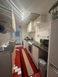 a kitchen with white cabinets and a red and white rug at Cosy Smart/Small Double Room in Keedonwood Road Bromley in Bromley