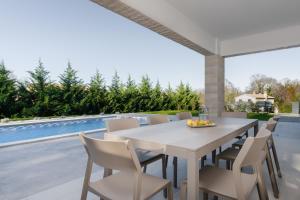 uma mesa branca e cadeiras num pátio com piscina em NEW! Modern Villa Themis Istria PRIVATE heated POOL em Kršan