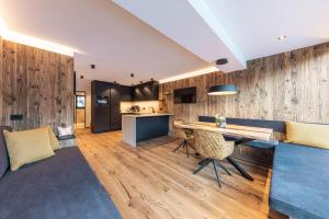 a kitchen and living room with a wooden wall at Enjoy Dolomites - Chalet in Santa Cristina Gherdëina