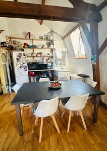 a kitchen with a black table and white chairs at Loft à partager in Seclin