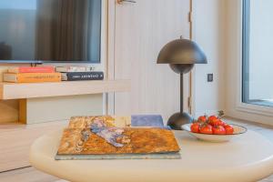 a table with a book and a bowl of tomatoes on it at Yuna Porte-Maillot - ApartHotel in Paris