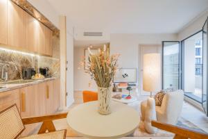 a living room with a table and a vase with flowers at Yuna Porte-Maillot - ApartHotel in Paris