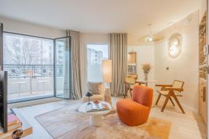 a living room with an orange chair and a table at Yuna Porte-Maillot - ApartHotel in Paris