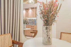 a vase with flowers on a table in front of a mirror at Yuna Porte-Maillot - ApartHotel in Paris