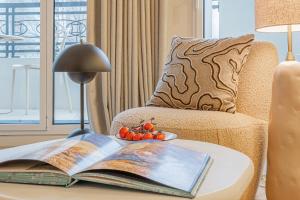 a table with a book and a lamp on a chair at Yuna Porte-Maillot - ApartHotel in Paris