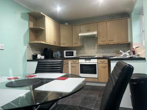 eine Küche mit Holzschränken und einem Tisch mit Stühlen in der Unterkunft Brades Rise House - 3 bedroom house with 2 toilets with a private garden in Birmingham