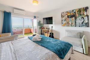 a bedroom with a bed and a couch and a television at Cozy beach studio retreat near Lisbon with Sea View in Almada