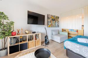 a bedroom with a bed and a tv on a wall at Cozy beach studio retreat near Lisbon with Sea View in Almada