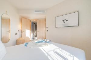 a bedroom with a white bed with a tv on the wall at Yuna Porte-Maillot - ApartHotel in Paris