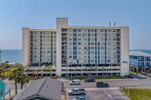 ein großes Gebäude mit Autos auf einem Parkplatz in der Unterkunft Oceans At The Grove By Hostique in Myrtle Beach