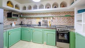 una cocina verde con armarios y electrodomésticos verdes en riad asmaa en Marrakech