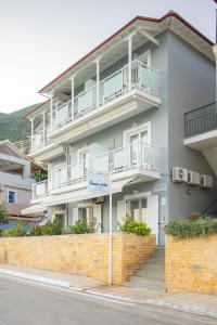 a white building with balconies and a brick wall at Romanza Studios in Vasiliki