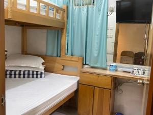 a bedroom with bunk beds and a desk with a television at Johnson Hostel in Hong Kong