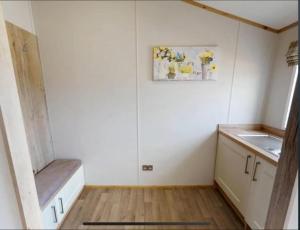a small kitchen with white walls and wooden floors at Golden Anchor - The Oakland Lodge - Coastal Caravan Breaks in Chapel Saint Leonards