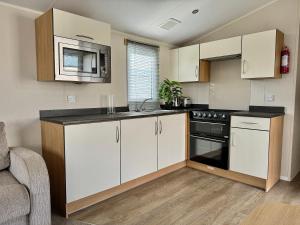 a kitchen with white cabinets and a stove top oven at Haven Seashore Holiday Park in Caister-on-Sea