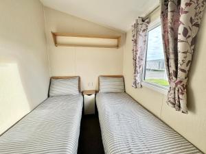 two beds in a small room with a window at Haven Seashore Holiday Park in Caister-on-Sea