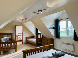 een slaapkamer op zolder met 2 bedden en een raam bij The Cow Shed in Narberth