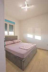 a bedroom with a large bed with pink sheets at Apartmani Lauc in Ljubuški