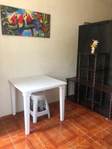een witte tafel en kruk in een kamer met een schilderij bij hospedaje Maluli suit 2 in Santa Elena