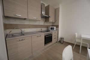 a kitchen with wooden cabinets and a sink and a microwave at B&B Nonna Maria in Pompei