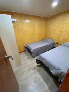 Habitación pequeña con 2 camas y puerta en Arriendo de cabaña centro osorno en Osorno