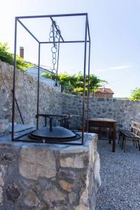 a stone wall with a fire pit and two benches at Old House Piperi in Podgorica