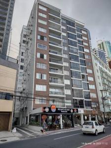 un coche aparcado frente a un edificio alto en Apartamento na Avenida Atlântica, en Balneário Camboriú