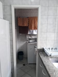 una pequeña cocina con fregadero, lavadora y secadora en Apartamento na Avenida Atlântica, en Balneário Camboriú