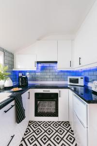 a kitchen with white cabinets and blue tiles at Central Retreat in Cardiff