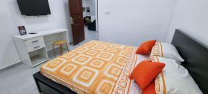 高爾的住宿－Wis Villa，一间卧室配有一张带橙色枕头的床和一张书桌