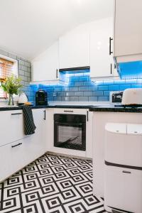 a kitchen with white cabinets and blue tiles at Central Retreat in Cardiff