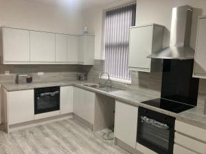 a kitchen with white cabinets and a sink at Riverside by Teil in Preston