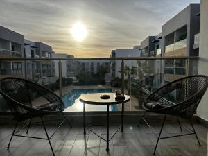a balcony with a table and two chairs and a pool at Sunny Apartment with Pool View & Terrace in Casablanca