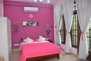 高爾的住宿－Wis Villa，粉红色的卧室,配有一张床和粉红色的墙壁