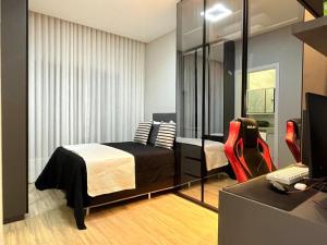 a bedroom with a bed and a desk with a computer at Casa para fins de semana in Maringá