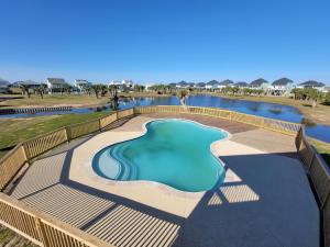 a swimming pool with a deck and a pond at Galveston Beach House w Water Views & New Pool in Galveston