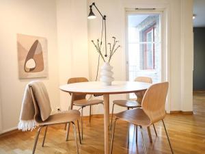 Live in a stylish home in the center of Oslo في أوسلو: طاولة طعام مع كراسي و مزهرية عليها