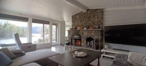a living room with a fireplace and a tv at Gauvik - Lyngdal in Lyngdal