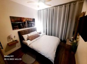 Un pequeño dormitorio con una cama blanca y una ventana en Sea View Suites - דירות נופש עם מקלט en Caesarea