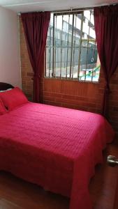 a red bed in a room with a window at Apartamento Ciudad Salitre Bogota - Amoblado in Bogotá