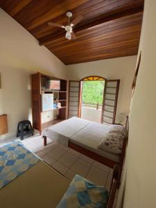 a bedroom with two beds and a ceiling fan at Pousada Stilo Ponta Negra in Ubatuba
