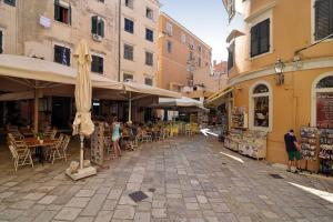 a street with people sitting at tables and umbrellas at Venetian Suite Mitropolis new in Corfu