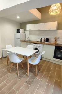 a kitchen with a white table and white chairs at Appartement au cœur du village, climatisé avec extérieur in Gréoux-les-Bains