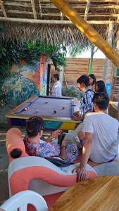 um grupo de pessoas sentadas à volta de uma mesa de bilhar em Hostal El Cascol em Puerto López