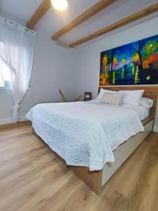 1 dormitorio con 1 cama grande y una pintura en la pared en El Hogarin de Veronica en Gijón