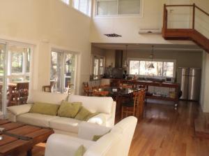 sala de estar con sofá blanco y cocina en La casa de 10GO en Cariló